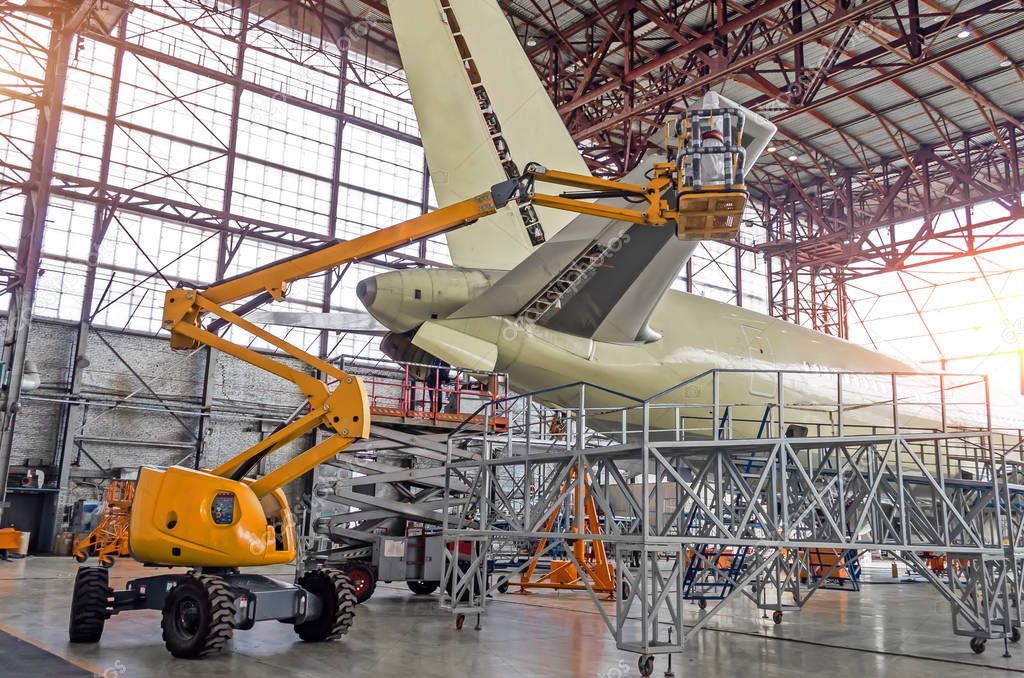 Large passenger aircraft on service in an aviation inside hangar rear view of the tail, on the auxiliary power unit