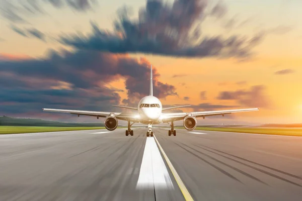 民間航空機は速度モーション ブラーで日没時滑走路空港で加速します — ストック写真