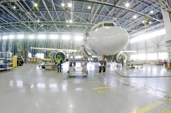 Passenger airplane on maintenance of engine, fuselage repair in airport hangar