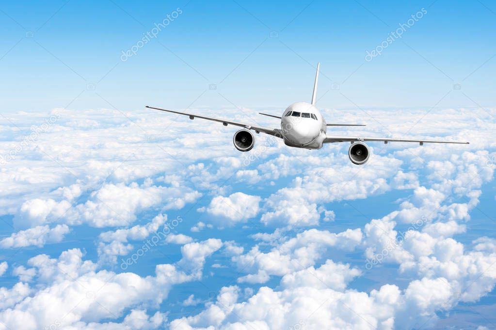 Airplane jet flying at flight level high in the sky above the clouds and blue sky