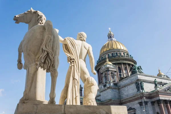 St. Isaac's Cathedral, in the foreground a sculpture of a male warrior with a horse in Saint-Petersburg