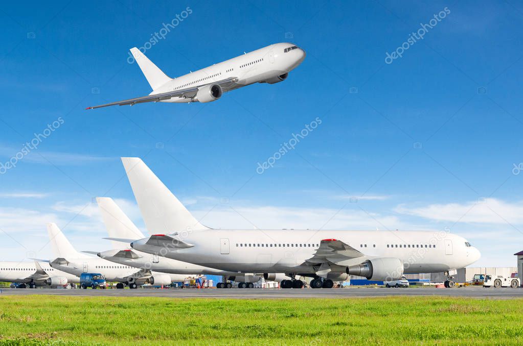 Airport with many airplanes and flying plane in the sky