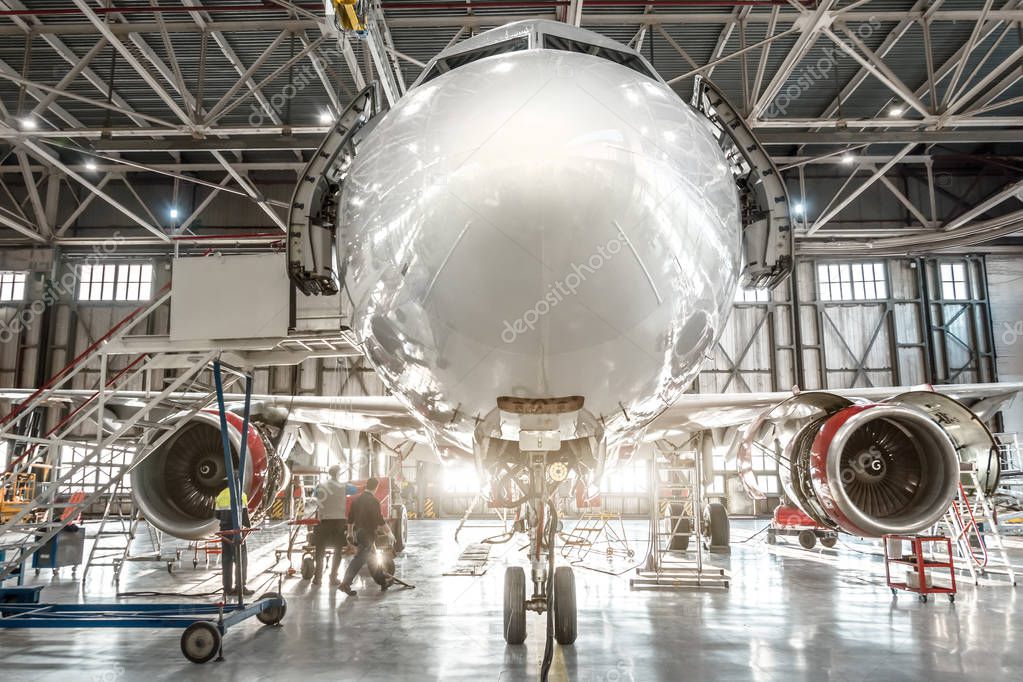 Passenger aircraft, nose close up. Maintenance of engine and fuselage repair in airport hangar.
