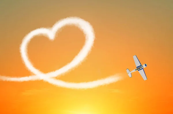 Light aircraft in the sky draws white smoke love heart.