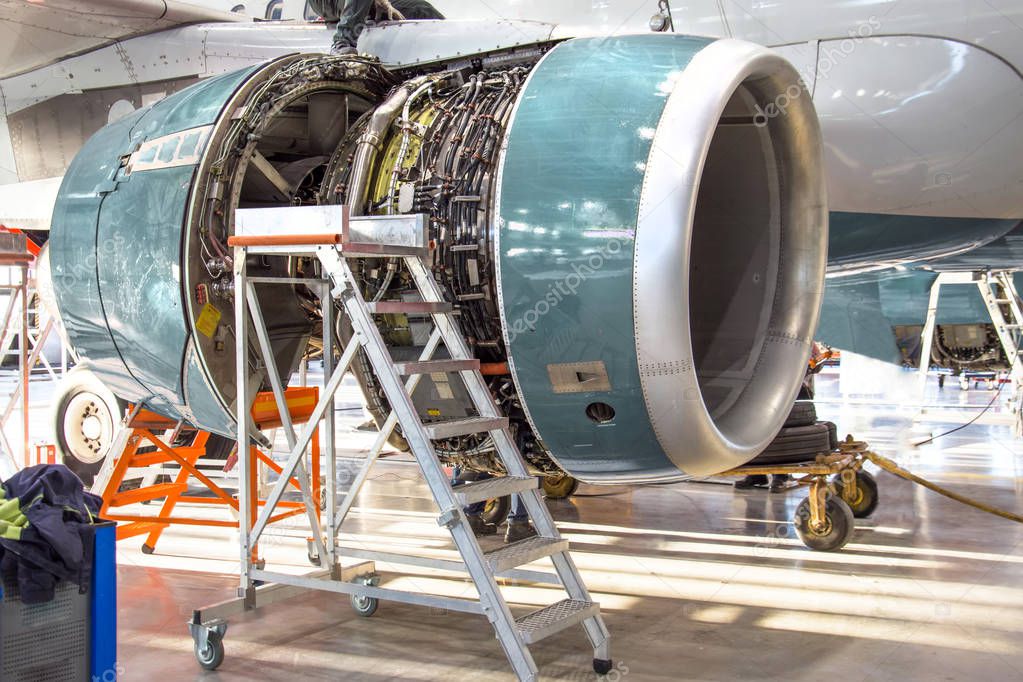 Maintenance, opened aircraft engine in the hangar in huge industrial hall.