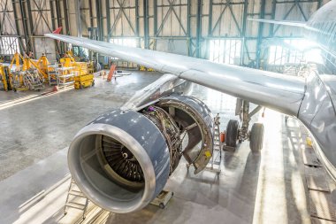 Hangarda, bakım açılan uçak motoru. Kanat görünümü.