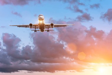 Plane on the glide path before landing on the background of a beautiful sunset and picturesque clouds