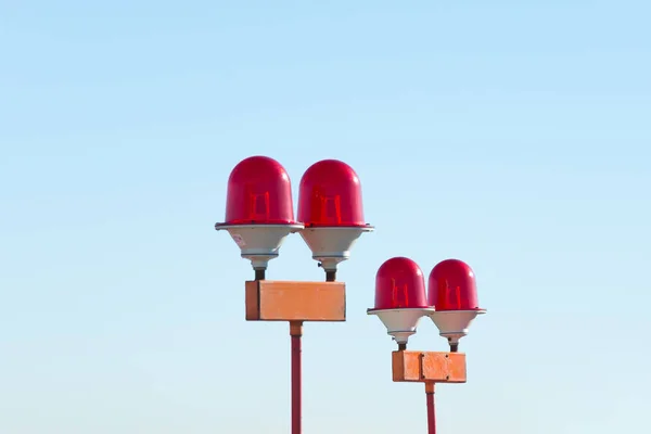 Red warning warning light with the light on, against the blue sky.