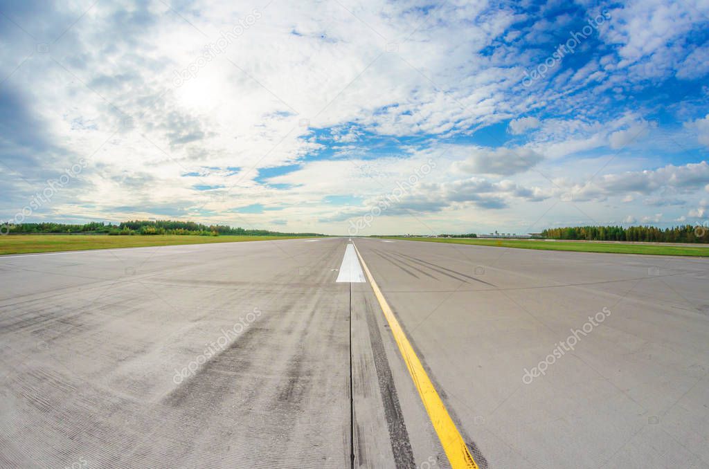 Runway clear for take off, airstrip with marking on blue sky with clouds background. Travel aviation concept.