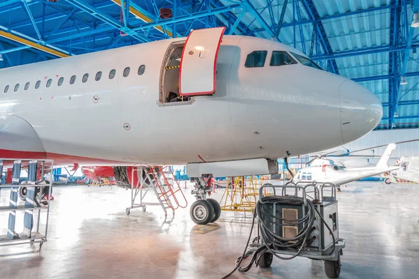 The nose of the aircraft fuselage with open door in the aircraft hangar