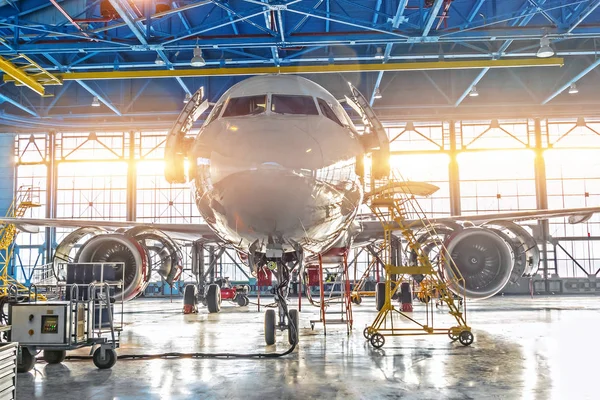Sivil uçak jet motoru ve gövde bakım onarım Havaalanı hangarda kontrol edin. Kapıdaki parlak ışık.