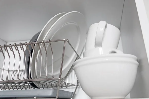 Кухонный шкаф с решеткой для посуды, с белой и черной тарелкой, чашки, и поднос с капельницей — стоковое фото