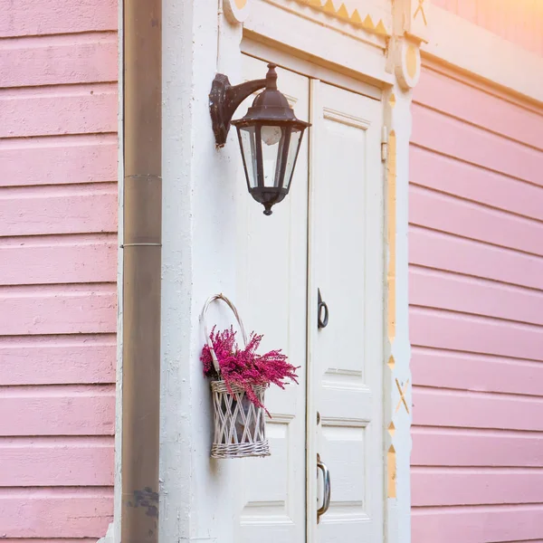 Porta branca para uma casa rosa com flores lilás e uma lâmpada de rua — Fotografia de Stock