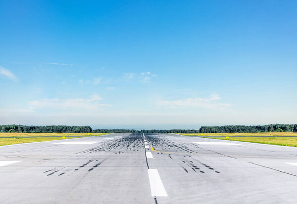 Empty runway at the airport on a sunny clear cloudless day.