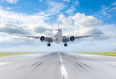 Uçak piste güneşli bir günde, arka plan yaz bulutlarda iniş..
