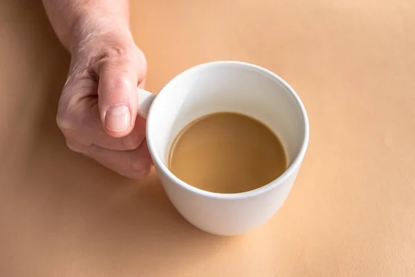 Elderly woman holds in hand morning coffee with milk in hand