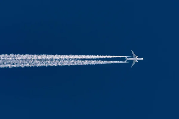 Avión vuela dejando rastro de la estela en un cielo azul claro . — Foto de Stock