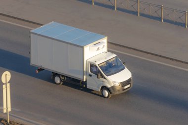 Several delivery van and white logistic truck driving on the highway.