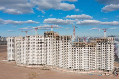 İnşaat vinçleri manzaralı büyük ölçekli bir konut kompleksinin havadan görünüşü.