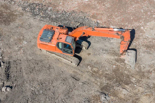 Escavadeira laranja em lagartas no poço de fundação durante a construção da fundação do edifício, escavação. Vista aérea superior . — Fotografia de Stock