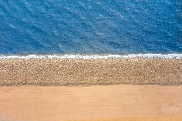 Frontera lisa entre mar y tierra. Montículo de piedras de arena y agua, vista aérea superior . — Foto de Stock