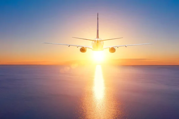 Airplane flies on a trip over the sea to the sunset. Summer vacation.