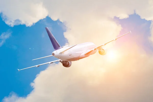 Uzak ülkelere seyahat edin. Uçak bulutların içinde parlak güneşe doğru irtifa kazanarak uçar.. — Stok fotoğraf