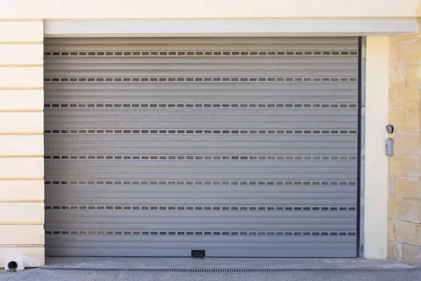 Automatic gray garage door, closed, with a bell at the door.