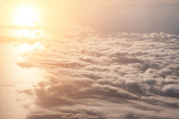 Luftaufnahme aus der Höhe des Fluges über den Wolken, die Sonne spiegelt sich in der Spiegeloberfläche des Meeres. — Stockfoto