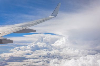 Yaz bulutlarının üzerinde uçan bir uçağın kanadı.
