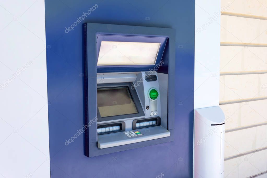 ATM cash machine in the wall of a building on a city street, operating and functional, no people near.