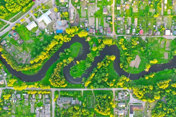 Flygvy landskap av slingrande liten flod bland den lilla staden, ström i grönt fält. — Stockfoto