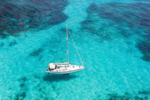 Aerial view of white yacht with moored sails in a tropical paradise lagoon turquoise water.