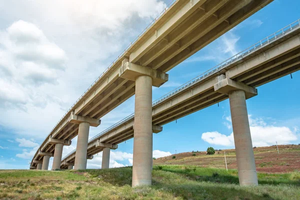 Twee weg afslag snelwegbrug, viaduct ondersteunt in de vallei tussen de groene heuvels, transport infrastructuur. — Stockfoto