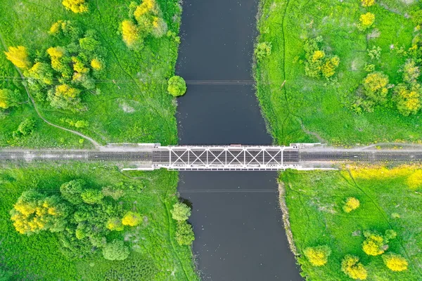 Järnvägsbro bland gröna ängar över en liten å på landsbygden, flygutsikt. — Stockfoto