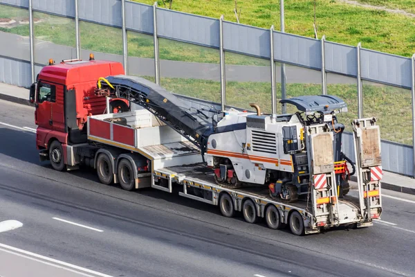Transportation of equipment for cutting old asphalt on a trailer truck platform on the highway. — Stock Photo, Image