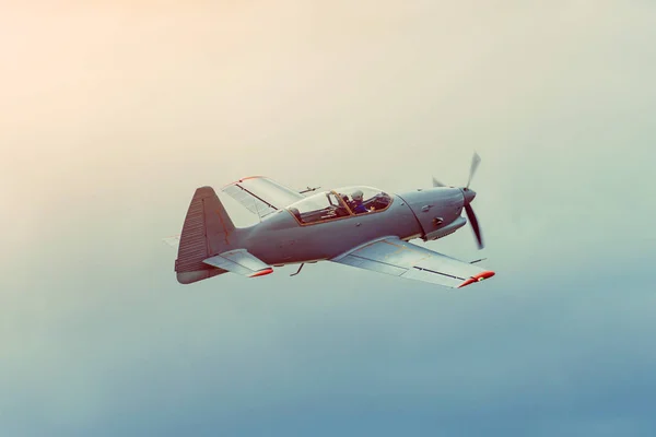 灰色の空を飛ぶ単一のプロペラ航空機曲技飛行. — ストック写真