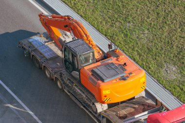 Ağır makine, yüklü Ekskavatör taşınması için uzun bir römork platformu ile kamyon. Karayolu taşımacılığı.