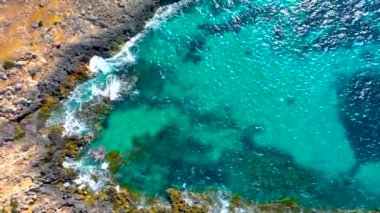 Sahildeki kayalara vuran deniz dalgalarının havadan görünüşü.