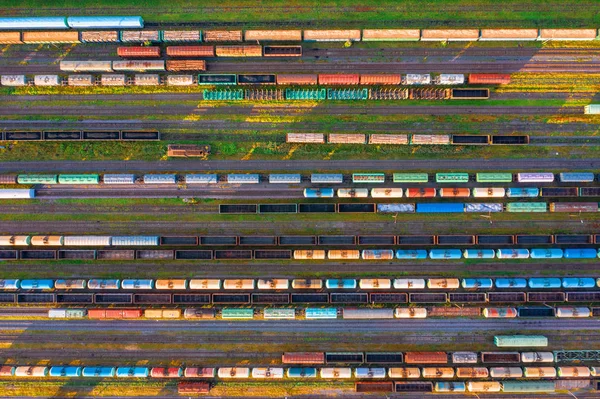 Vista aérea da estação ferroviária de triagem de carga com carros ferroviários, com muitos trilhos ferroviários ferrovia. Paisagem da indústria pesada na luz do pôr do sol à noite . — Fotografia de Stock