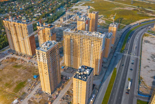 Vista aérea superior construção em larga escala de um complexo residencial com vista para guindastes de construção e estrada de asfalto . — Fotografia de Stock