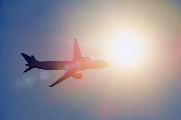 눈부심으로 밝은 태양을 향해 날아가는 비행기 실루엣. — 스톡 사진