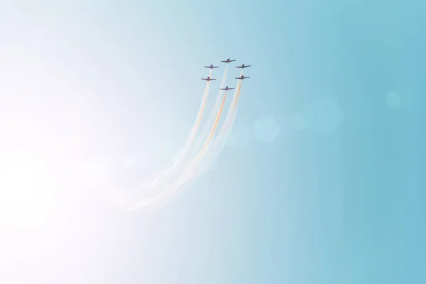 Groep van straaljagers vliegen tegen een heldere blauwe hemel, het uitvoeren van figuren uit de rook. — Stockfoto