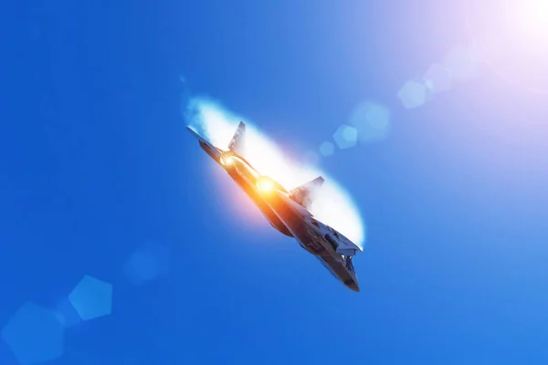 Combat fighter flies performing a maneuver in the air with clouds behind the wings, low pressure area. Sun glare from the bright sun and light from the nozzle of the afterburner. — Stock Photo, Image