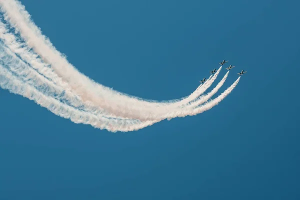 Aviones de combate volando contra un cielo brillante, realizando figuras se convierte del humo . — Foto de Stock