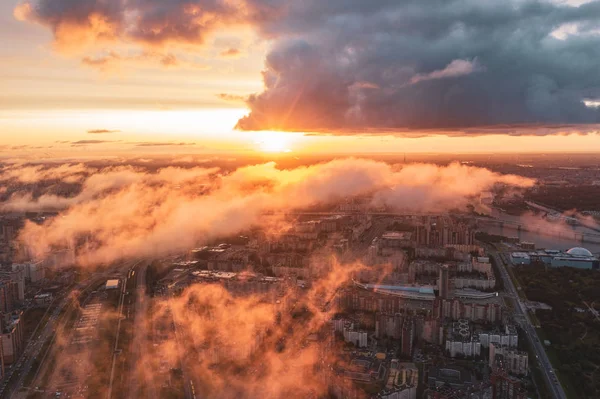Krajobraz miejski, widok z lotu ptaka z niskim latające chmury nad dzielnicy mieszkalnej miasta, widok na horyzoncie i świt słońca. — Zdjęcie stockowe