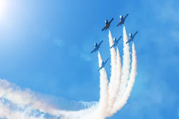 Parlak bir gökyüzüne karşı uçan savaş uçakları, performans rakamları dumandan döner. — Stok fotoğraf
