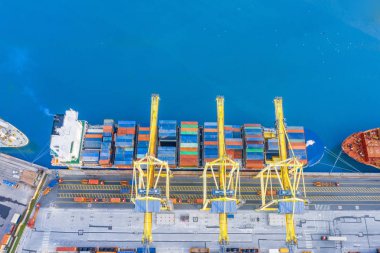 Liman rıhtımının yüksekliğinden havadan görünüm, konteyner boşaltma beklentisiyle okyanustan gelen demirlemiş kargo gemisi.