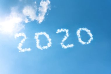 Sayılar 2020 sembol yazıt parlak bir güneş tarafından aydınlatılmış bulutların beyaz duman mavi gökyüzü bir arka plan üzerinde.