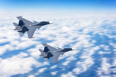 Bulutların arka planına karşı bir savaş görevi uçan yüksek hızda gökyüzünde iki savaşçı jet.